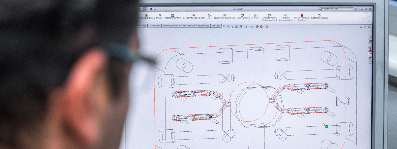 Employee in tool design in front of computer showing 3D image of die casting tool