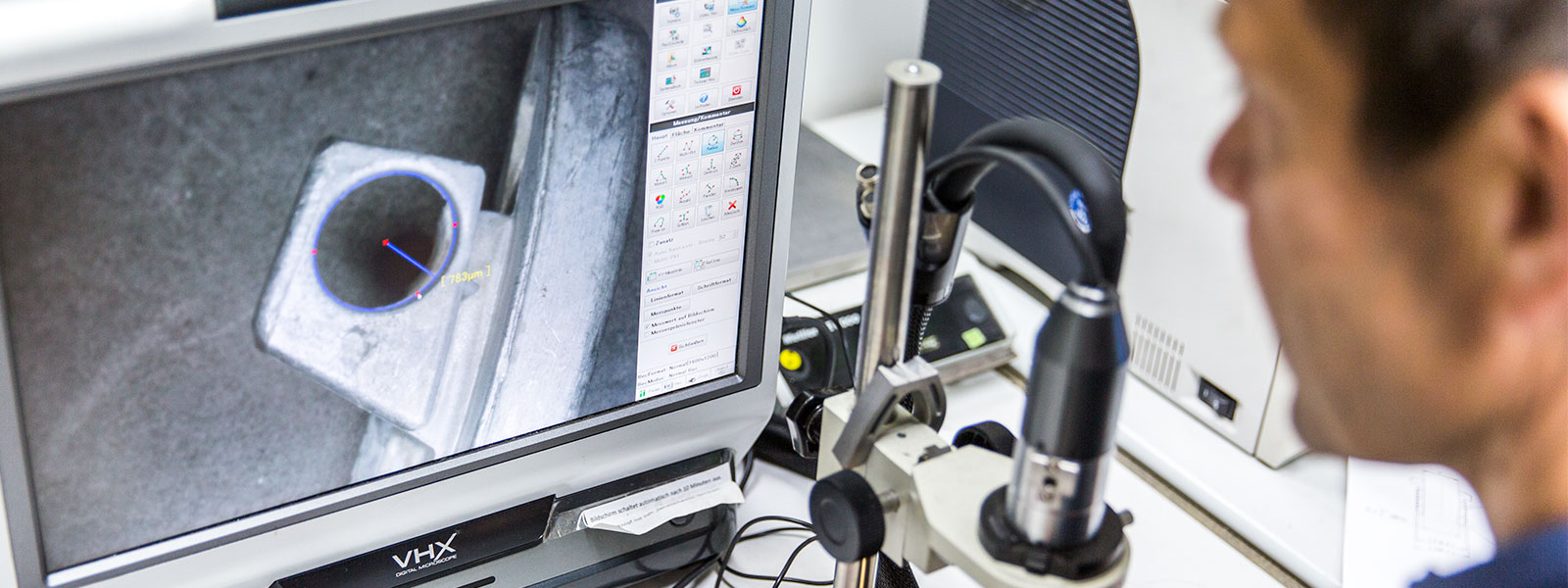 Employees performing microscopic analysis of the surface of a zinc die cast component