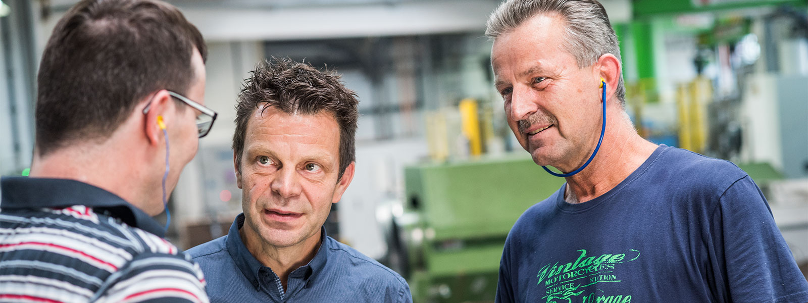 Drei Mitarbeiter von Druckguss Westfalen Behringer in der Produktionshalle im Gespräch